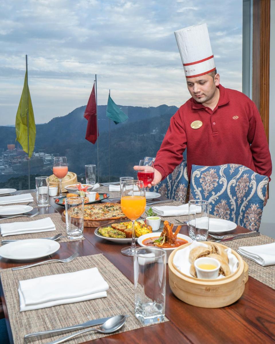 a man in a chefs hat standing at a table with food at WelcomHeritage Elysium Resort & Spa in Shimla