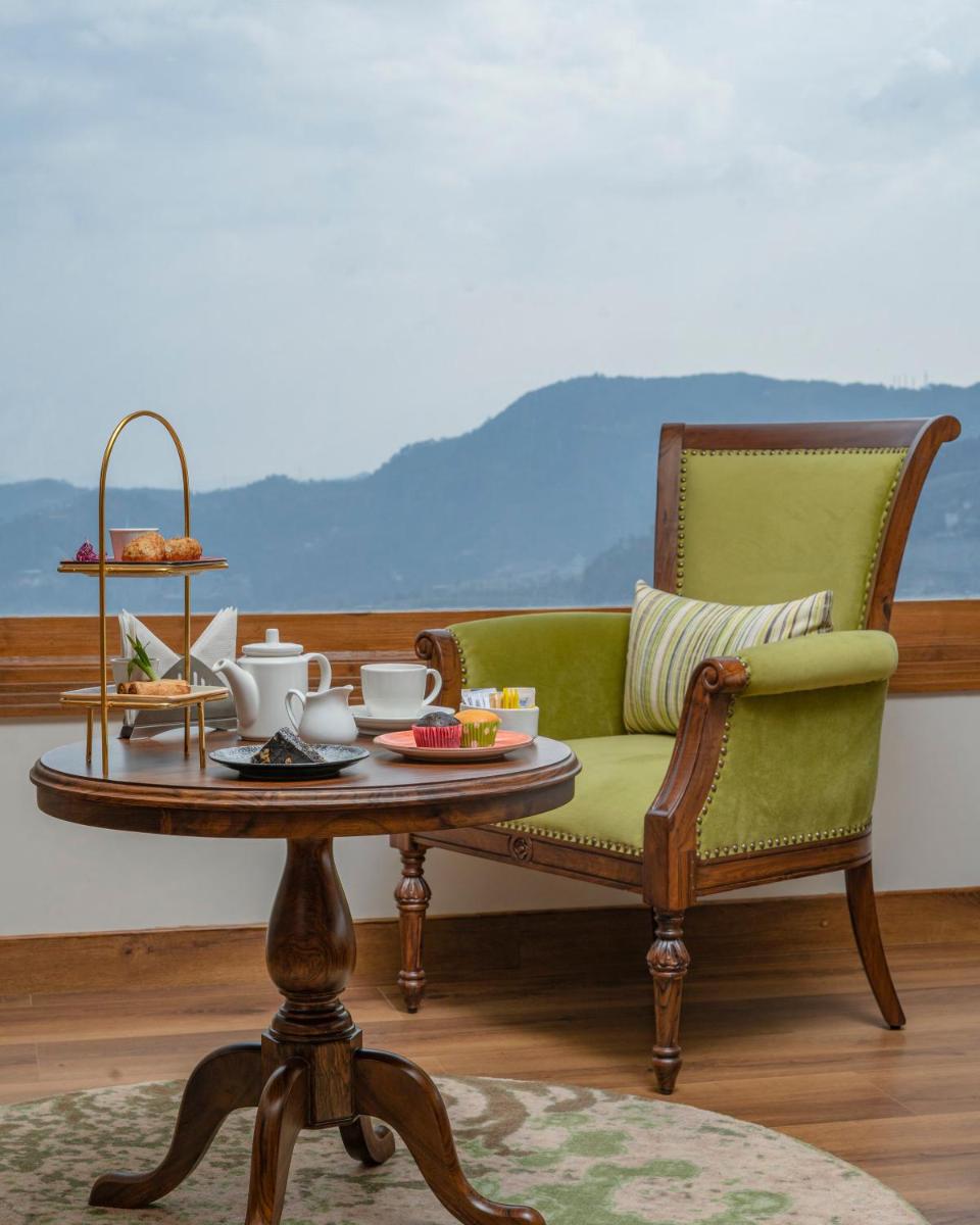 a living room with a green couch and a coffee table at WelcomHeritage Elysium Resort & Spa in Shimla