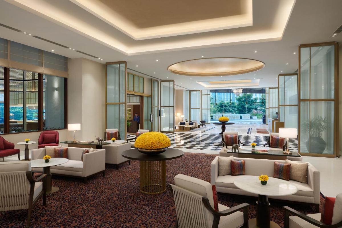 a hotel lobby with couches and tables and windows at The Leela Bhartiya City Bengaluru in Bengaluru a hotel lobby with couches and tables and windows at The Leela Bhartiya City Bengaluru in Bengaluru
