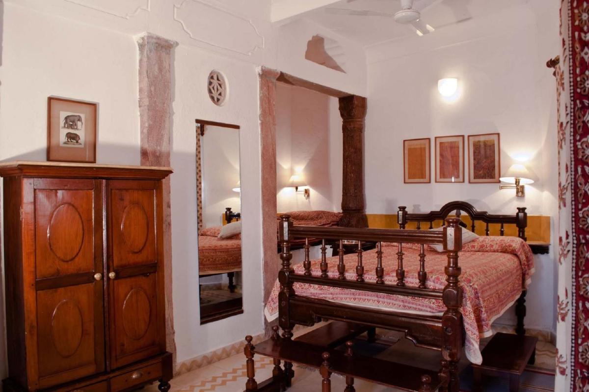 a bedroom with a bed and a dresser and a mirror at Neemrana Fort-Palace in Neemrana
