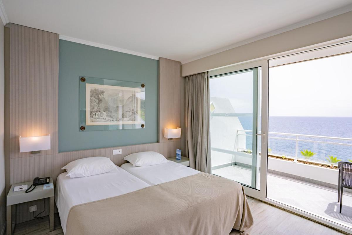 um quarto de hotel com uma cama e uma janela grande em Hotel Orca Praia no Funchal