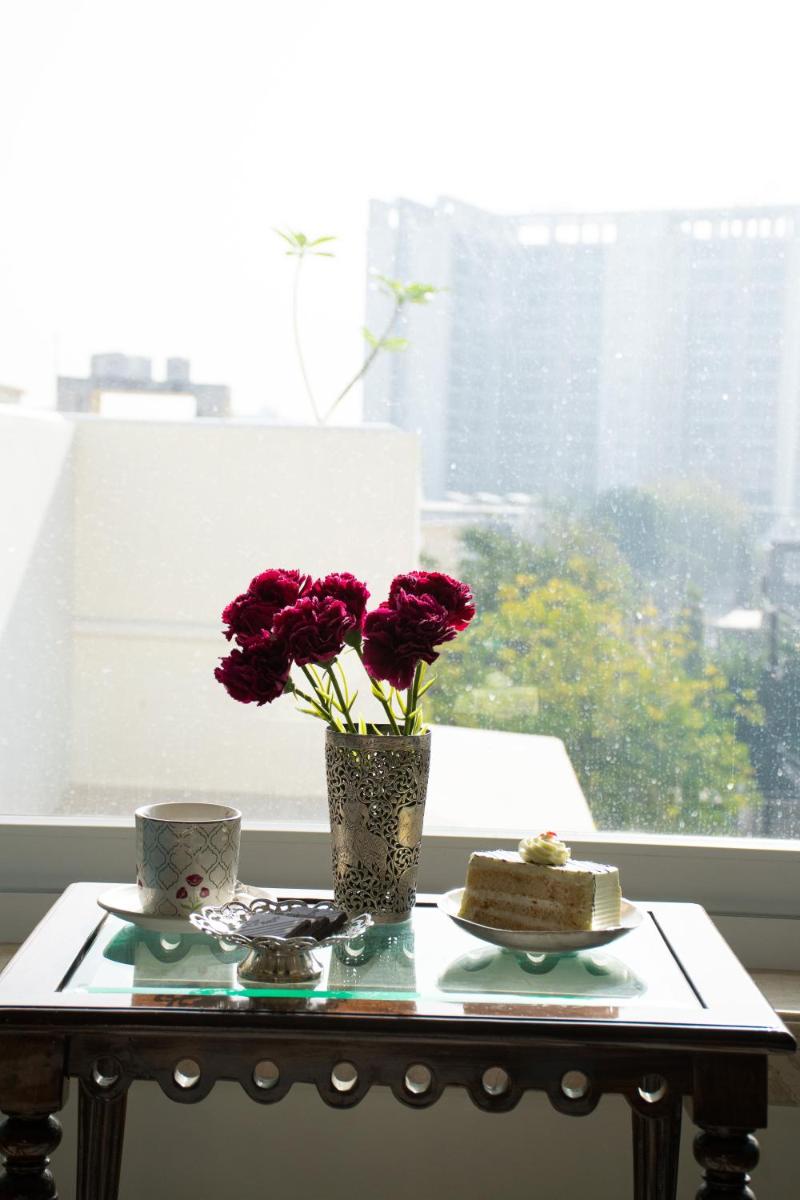 a table with flowers and a cake in a window at Dileep Kothi - A Royal Boutique Luxury Suites in Jaipur in Jaipur