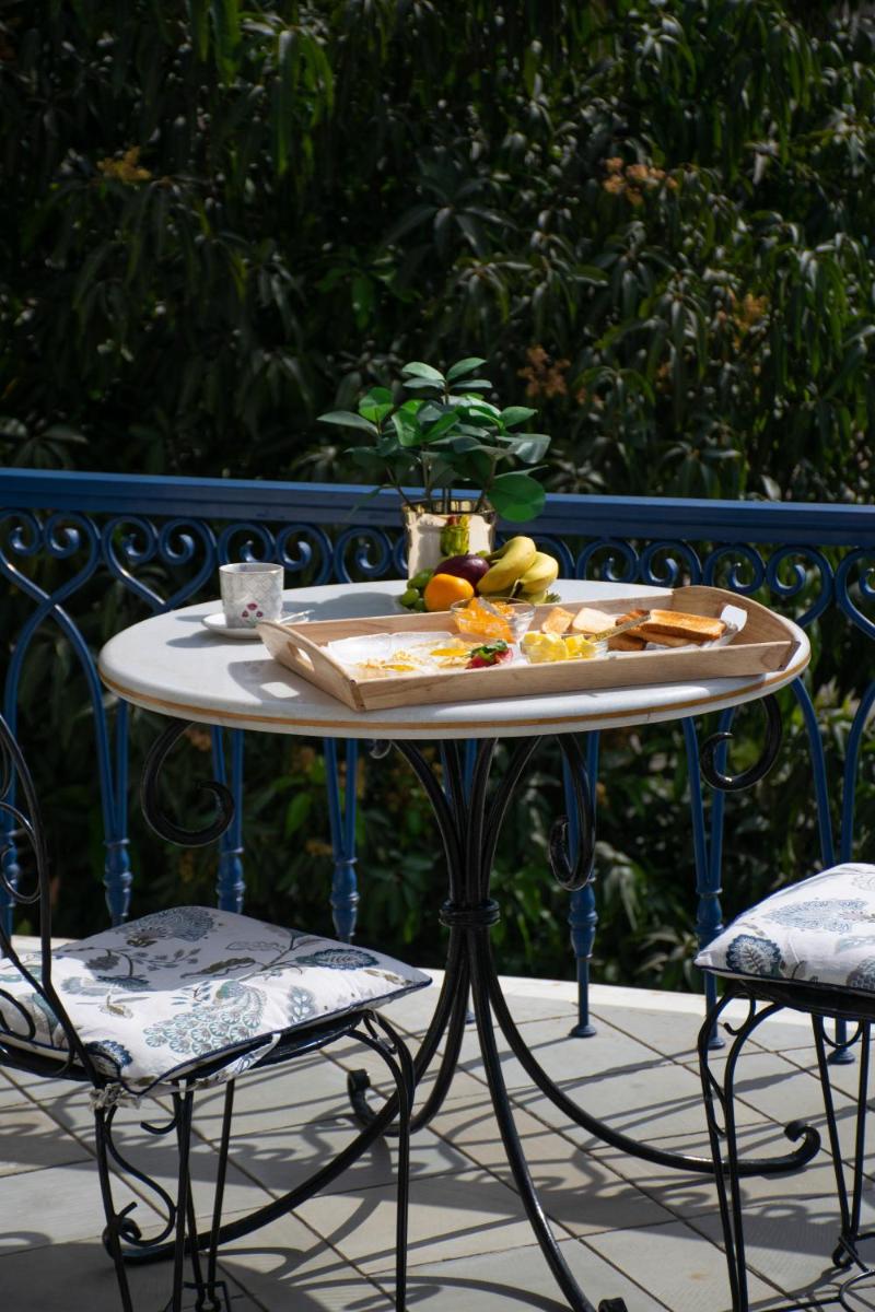 a table with a plate of fruit on it with two chairs at Dileep Kothi - A Royal Boutique Luxury Suites in Jaipur in Jaipur