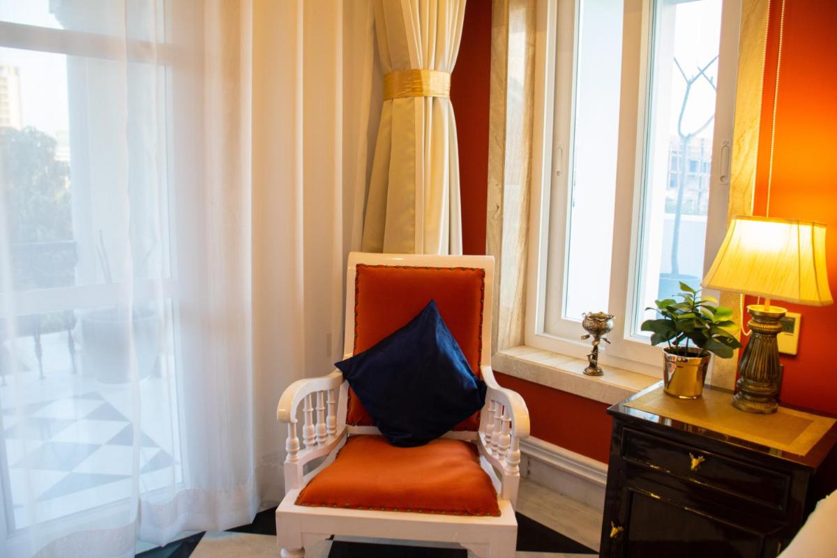 a chair with a pillow on it in front of a window at Dileep Kothi - A Royal Boutique Luxury Suites in Jaipur in Jaipur