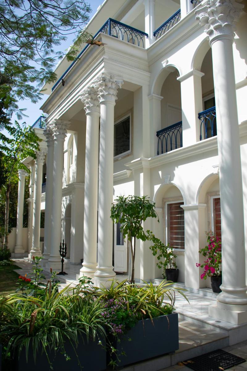 a large white house with columns and plants at Dileep Kothi - A Royal Boutique Luxury Suites in Jaipur in Jaipur