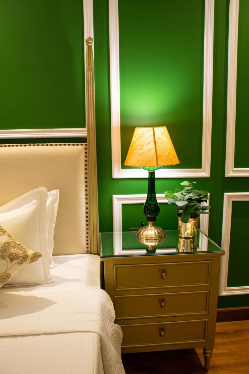 a bedroom with a green wall and a lamp on a dresser at Dileep Kothi - A Royal Boutique Luxury Suites in Jaipur in Jaipur