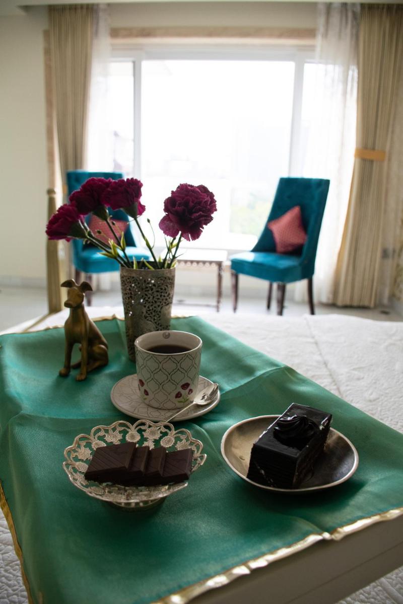a green table with two plates of chocolate cakes and a cup at Dileep Kothi - A Royal Boutique Luxury Suites in Jaipur in Jaipur
