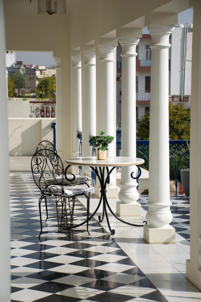 a table and chairs on a porch with columns at Dileep Kothi - A Royal Boutique Luxury Suites in Jaipur in Jaipur