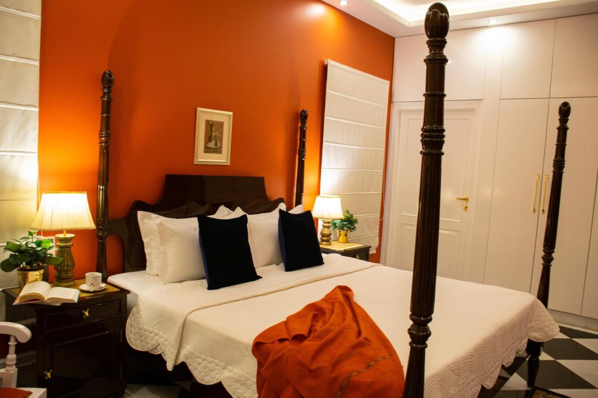 a bedroom with a bed with an orange wall at Dileep Kothi - A Royal Boutique Luxury Suites in Jaipur in Jaipur