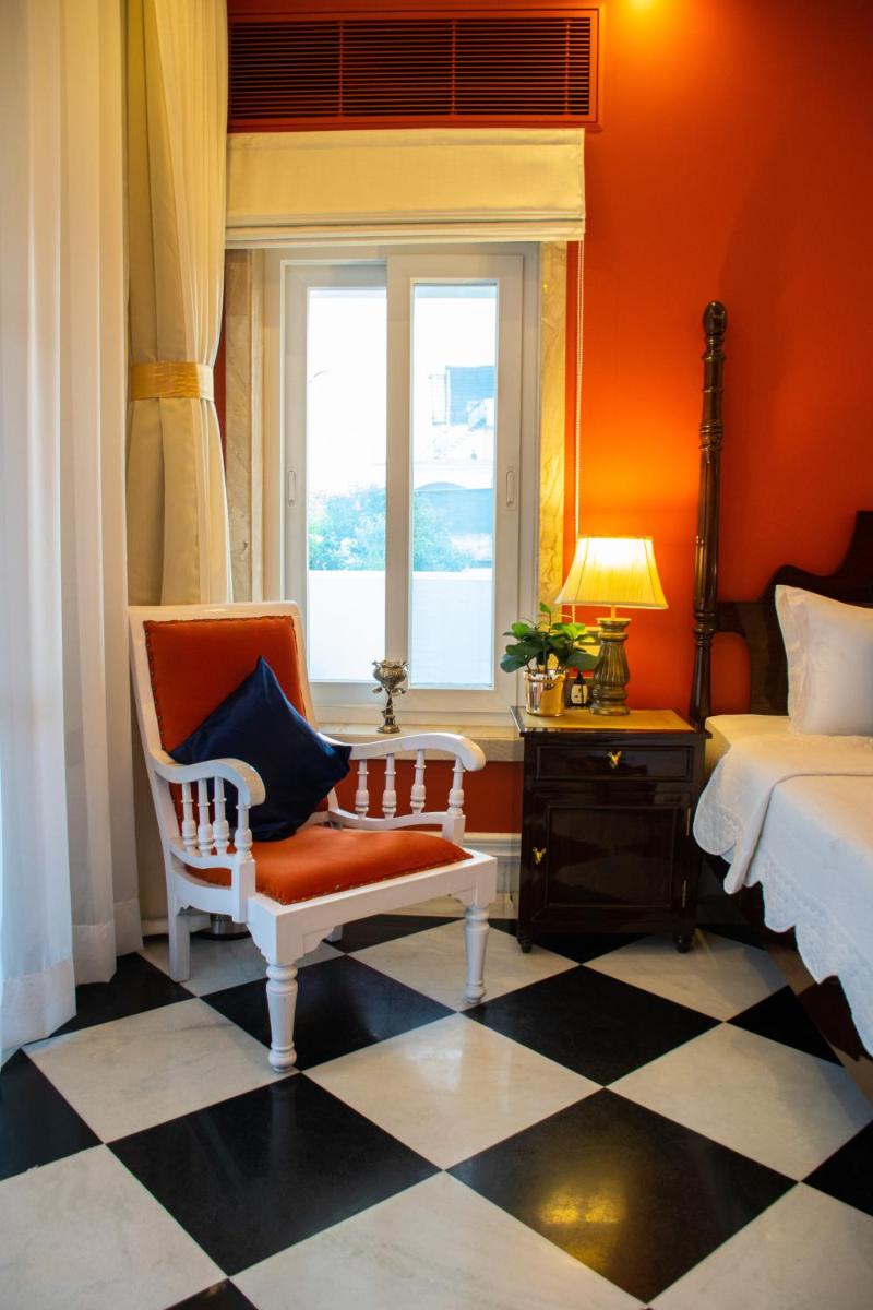 a bedroom with a bed and a chair and a window at Dileep Kothi - A Royal Boutique Luxury Suites in Jaipur in Jaipur
