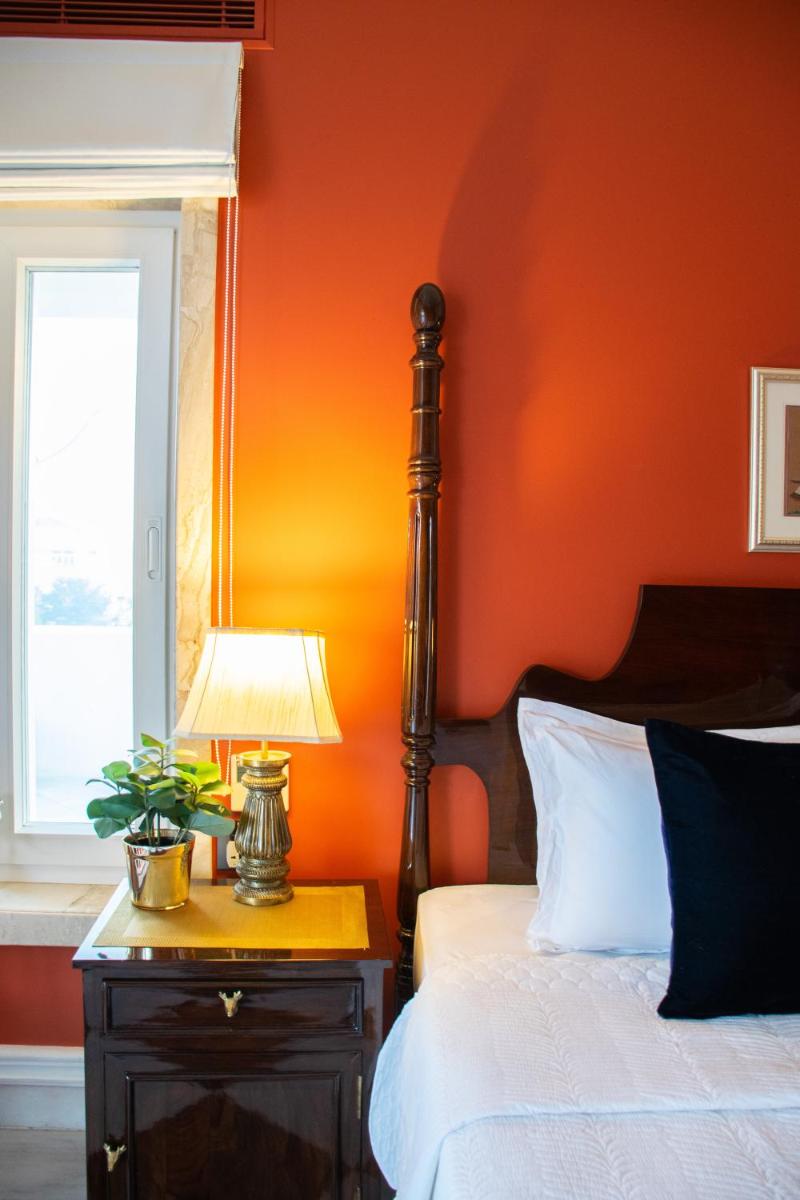 a bedroom with an orange wall with a bed and a lamp at Dileep Kothi - A Royal Boutique Luxury Suites in Jaipur in Jaipur