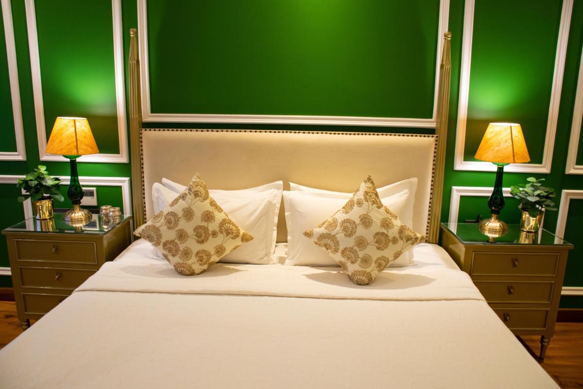 a bedroom with a white bed with green walls at Dileep Kothi - A Royal Boutique Luxury Suites in Jaipur in Jaipur