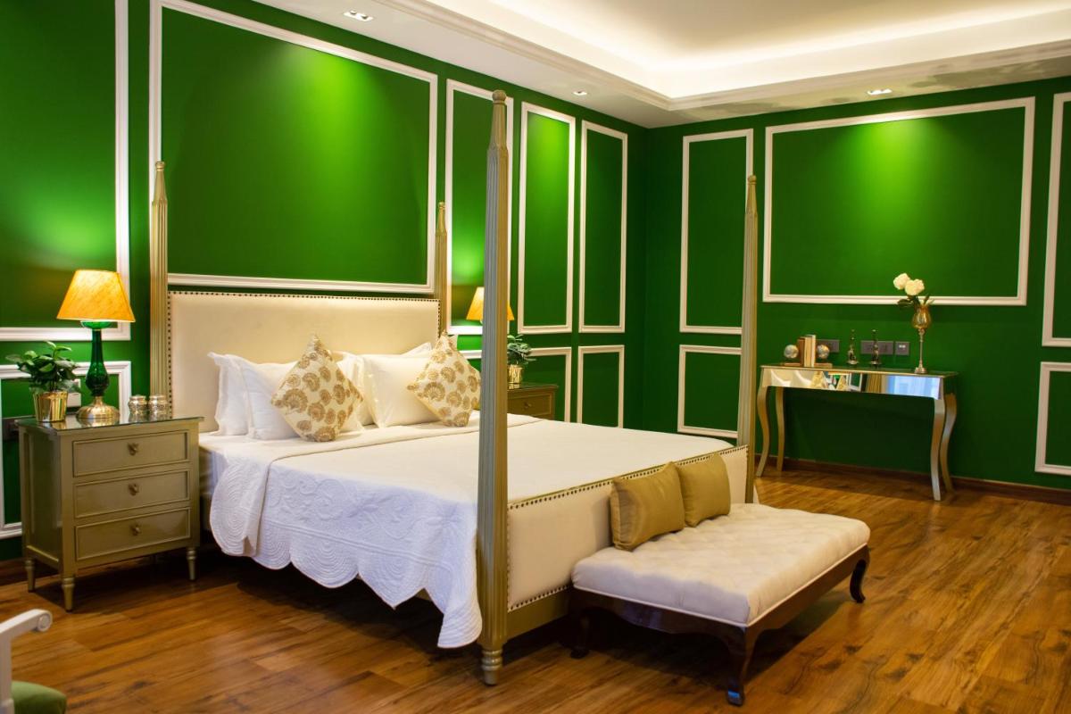a bedroom with green walls and a bed and a bench at Dileep Kothi - A Royal Boutique Luxury Suites in Jaipur in Jaipur
