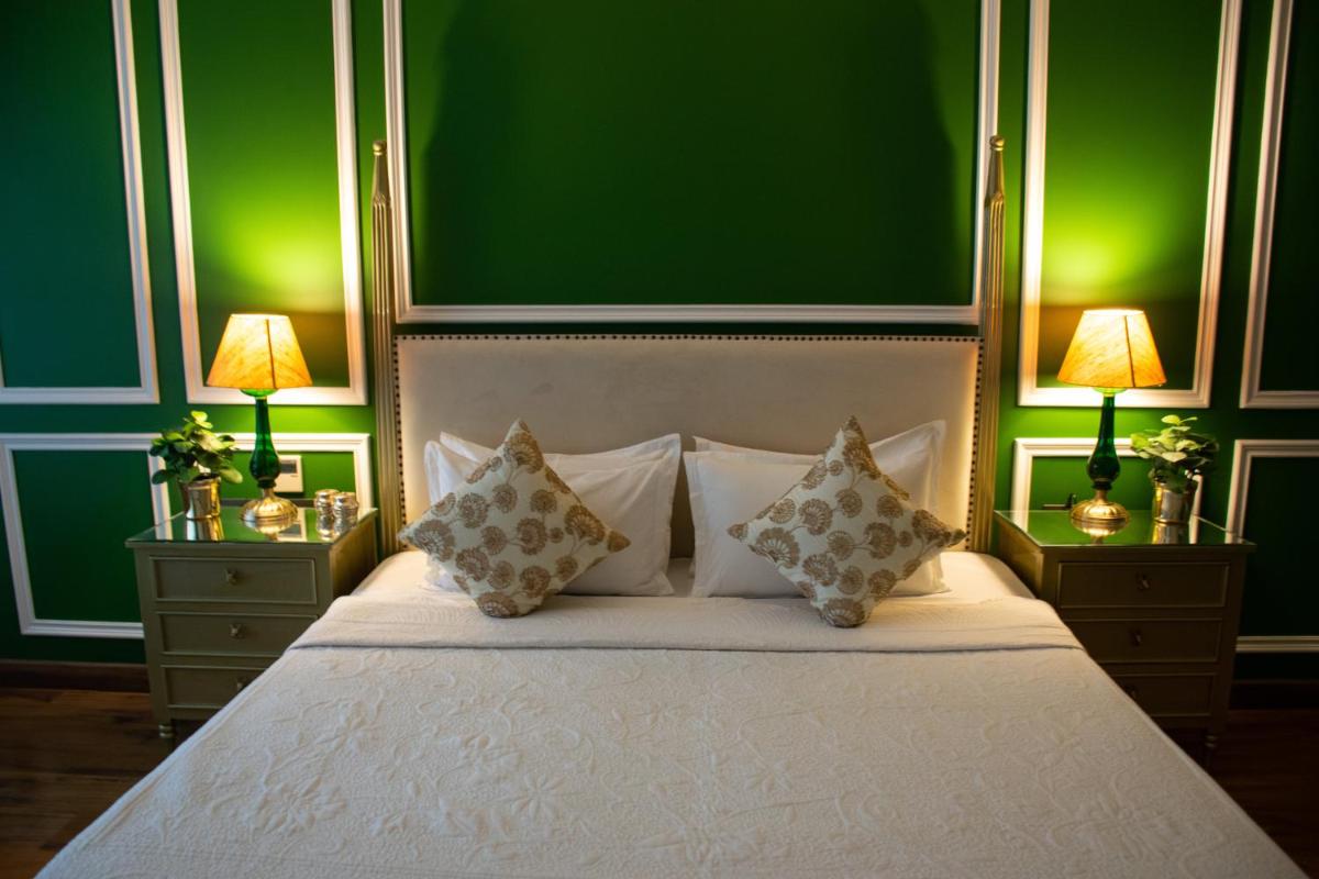 a bedroom with a white bed with green walls at Dileep Kothi - A Royal Boutique Luxury Suites in Jaipur in Jaipur