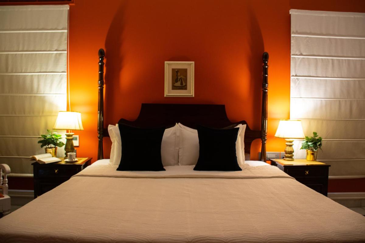 a bedroom with a large bed with an orange wall at Dileep Kothi - A Royal Boutique Luxury Suites in Jaipur in Jaipur