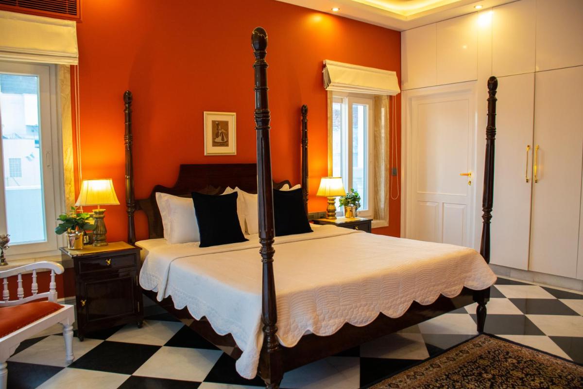 a bedroom with a bed with an orange wall at Dileep Kothi - A Royal Boutique Luxury Suites in Jaipur in Jaipur