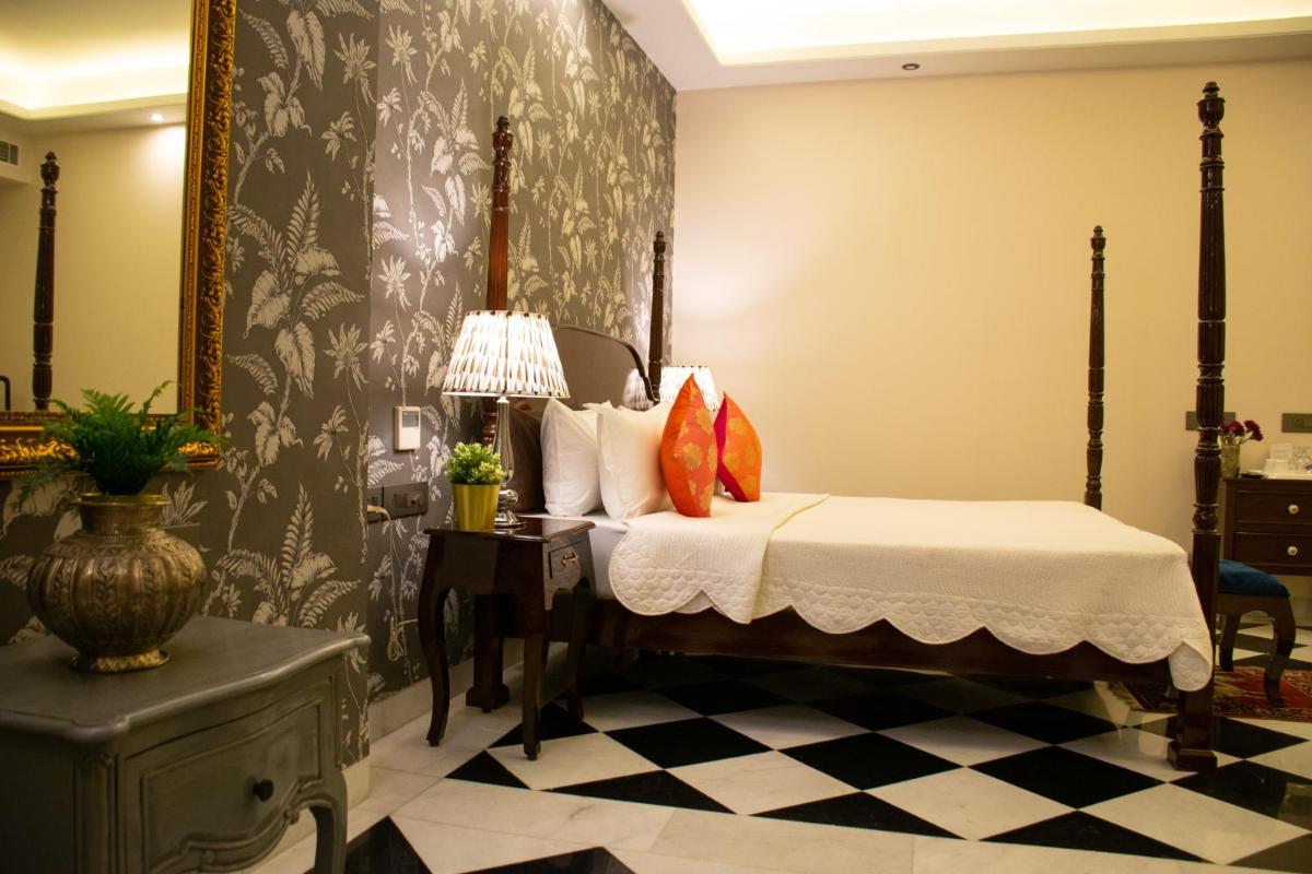 a bedroom with a bed and a table with a lamp at Dileep Kothi - A Royal Boutique Luxury Suites in Jaipur in Jaipur