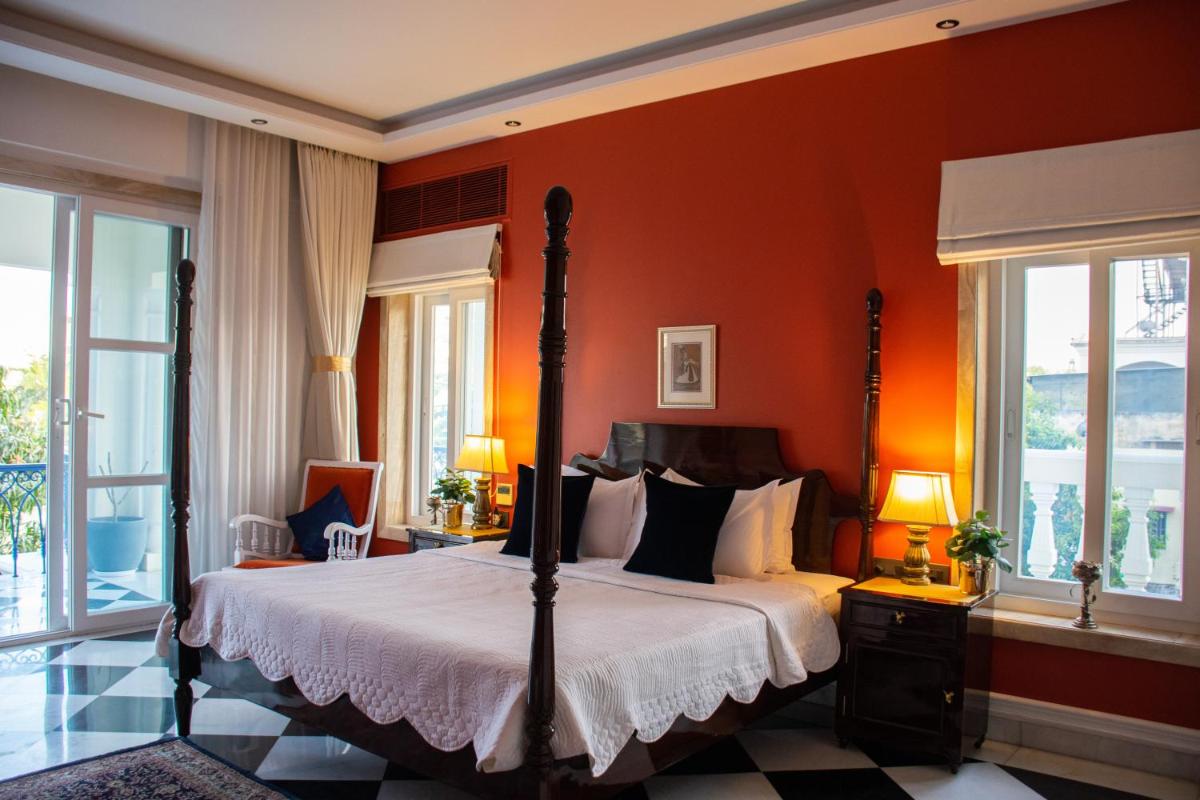 a bedroom with a bed with orange walls and windows at Dileep Kothi - A Royal Boutique Luxury Suites in Jaipur in Jaipur