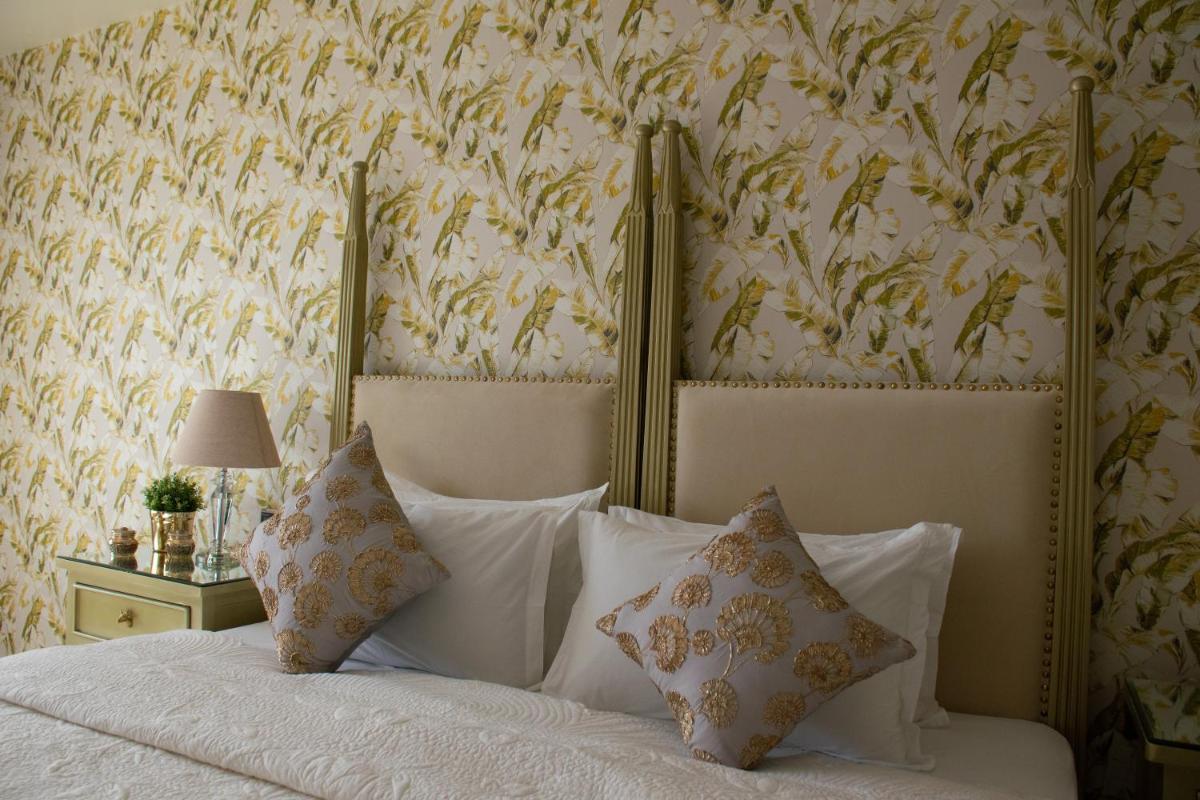 a bedroom with a bed with white pillows and wallpaper at Dileep Kothi - A Royal Boutique Luxury Suites in Jaipur in Jaipur