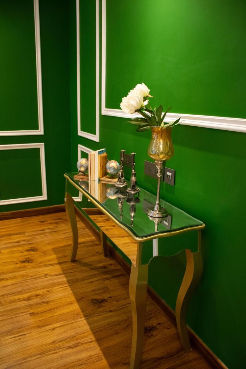 a green room with a table with a vase of flowers on it at Dileep Kothi - A Royal Boutique Luxury Suites in Jaipur in Jaipur