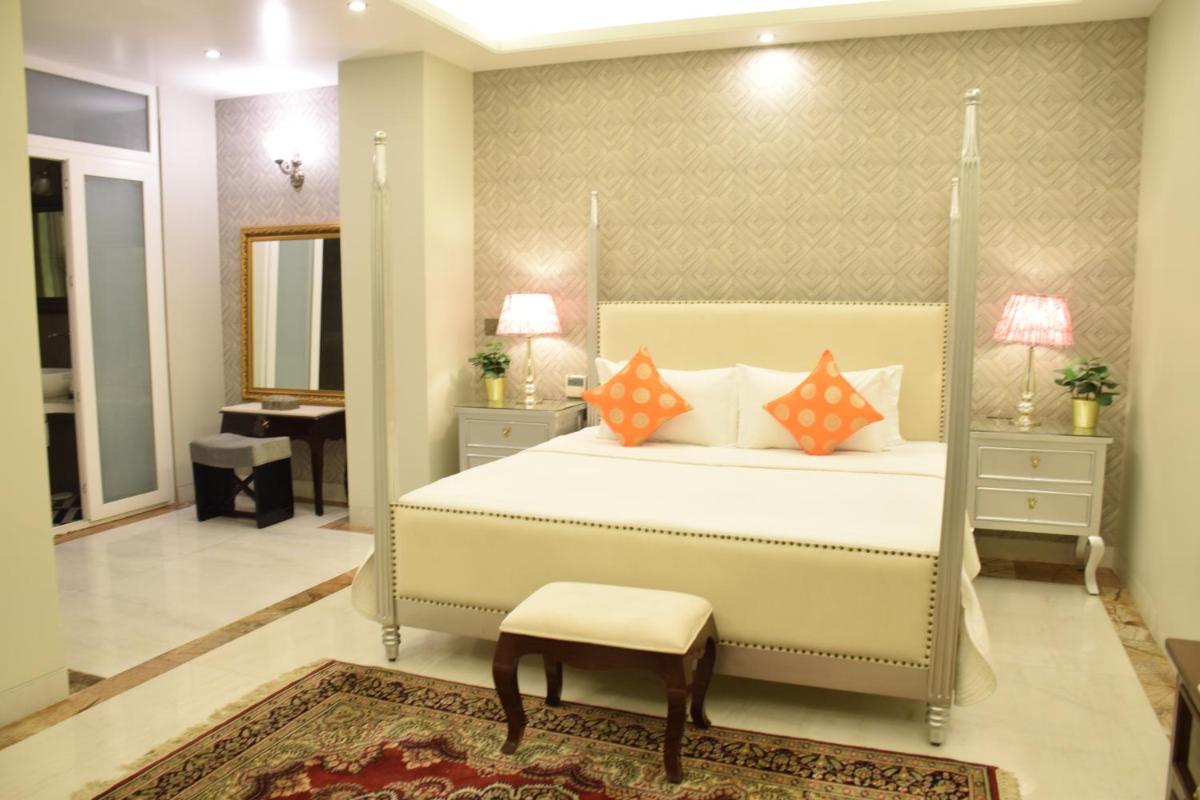 a bedroom with a bed with orange pillows and a stool at Dileep Kothi - A Royal Boutique Luxury Suites in Jaipur in Jaipur