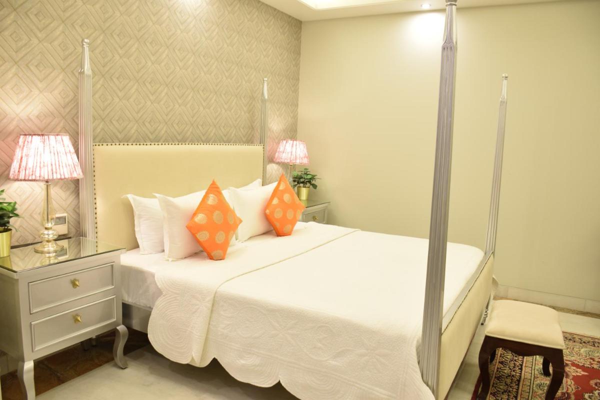 a bedroom with a large white bed with orange pillows at Dileep Kothi - A Royal Boutique Luxury Suites in Jaipur in Jaipur