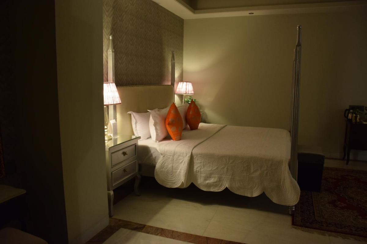 a bedroom with a bed with two orange pillows at Dileep Kothi - A Royal Boutique Luxury Suites in Jaipur in Jaipur