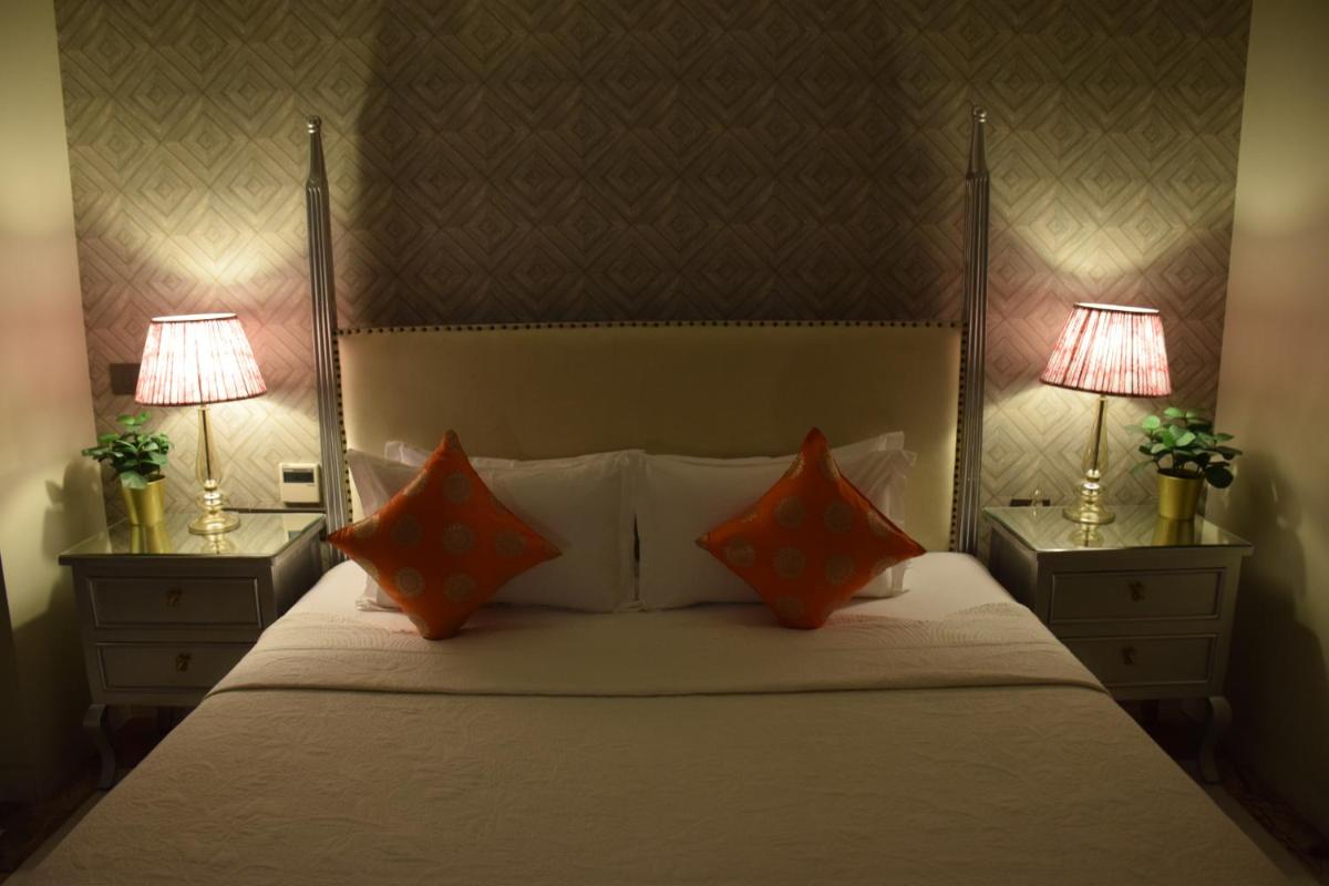 a bedroom with a bed with two lamps on both sides at Dileep Kothi - A Royal Boutique Luxury Suites in Jaipur in Jaipur