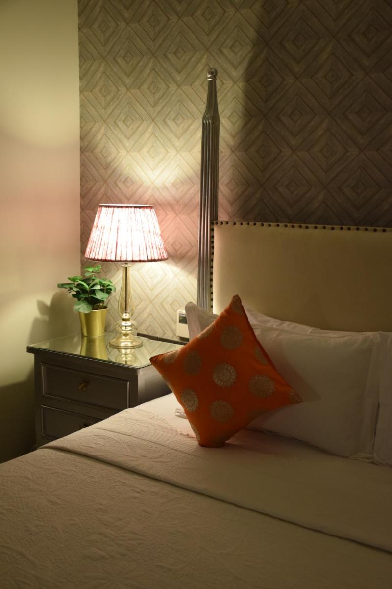 a bedroom with a bed with a lamp on a table at Dileep Kothi - A Royal Boutique Luxury Suites in Jaipur in Jaipur