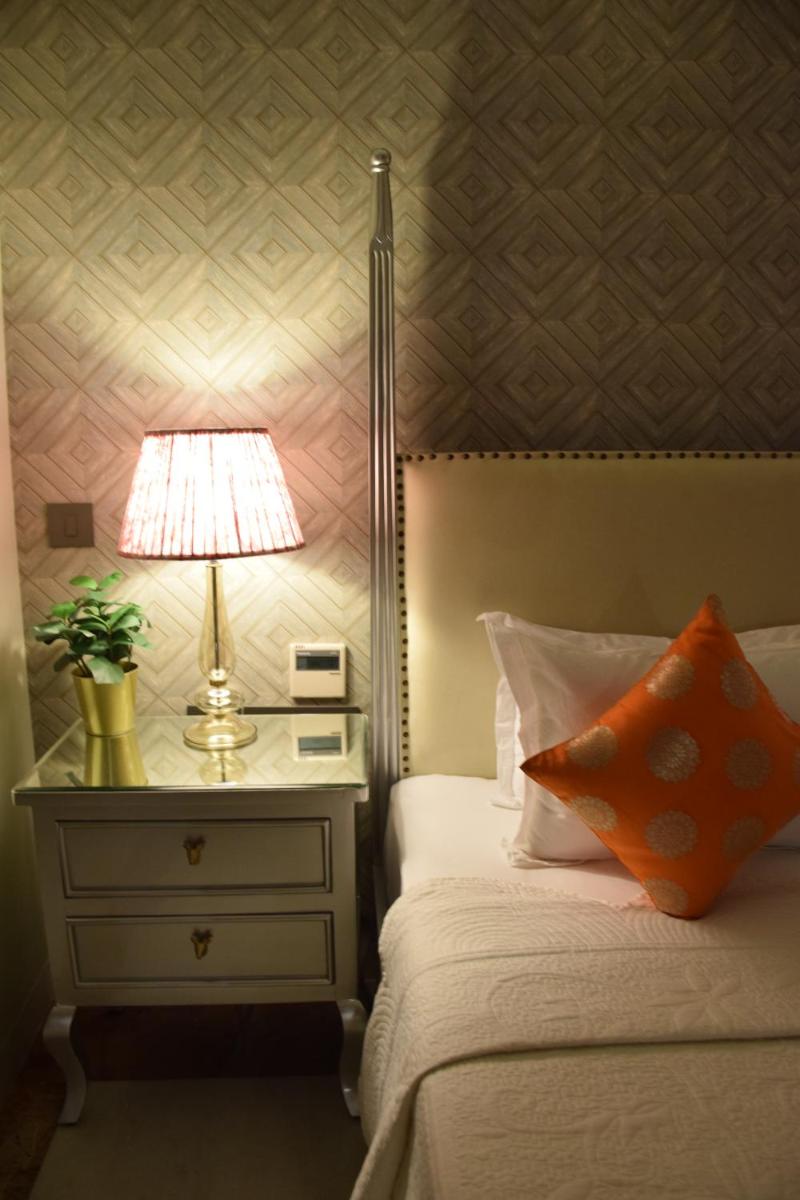 a bedroom with a bed and a lamp on a night stand at Dileep Kothi - A Royal Boutique Luxury Suites in Jaipur in Jaipur