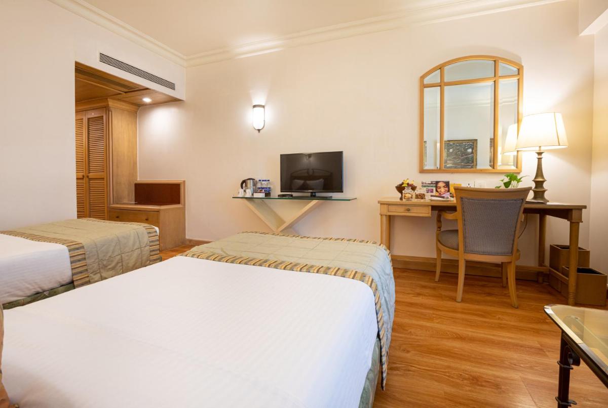 a hotel room with two beds and a desk at The Orchid Hotel Mumbai Vile Parle in Mumbai
