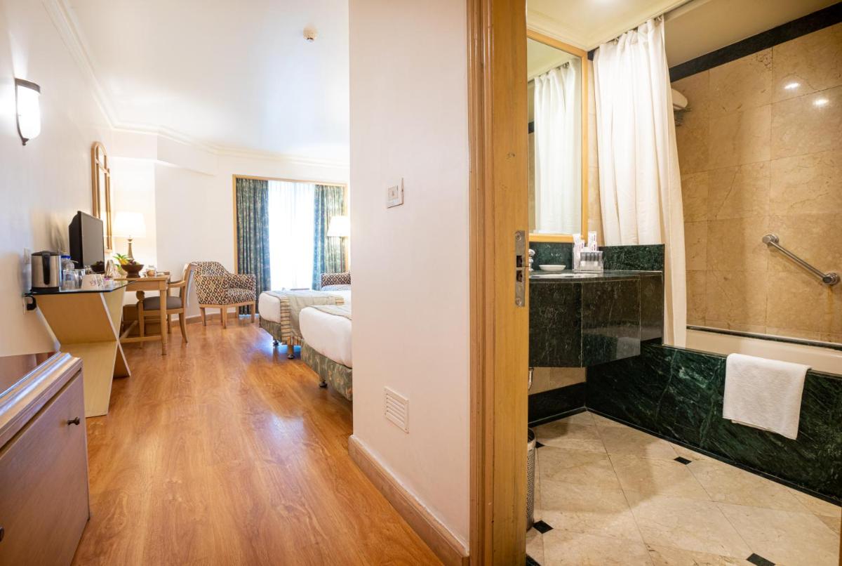 a bathroom with a large shower and a bedroom at The Orchid Hotel Mumbai Vile Parle in Mumbai