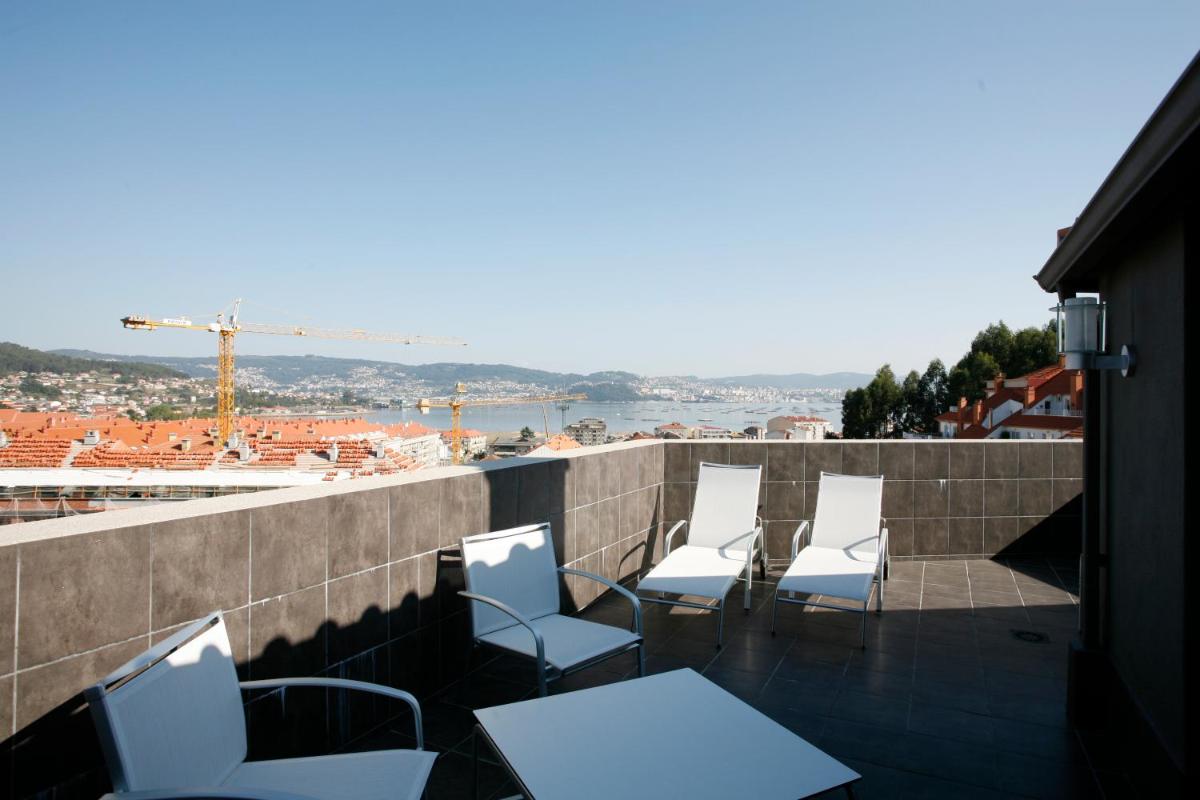 un grupo de sillas y mesas blancas en un balcón en Hotel Bienestar Moaña, en Moaña
