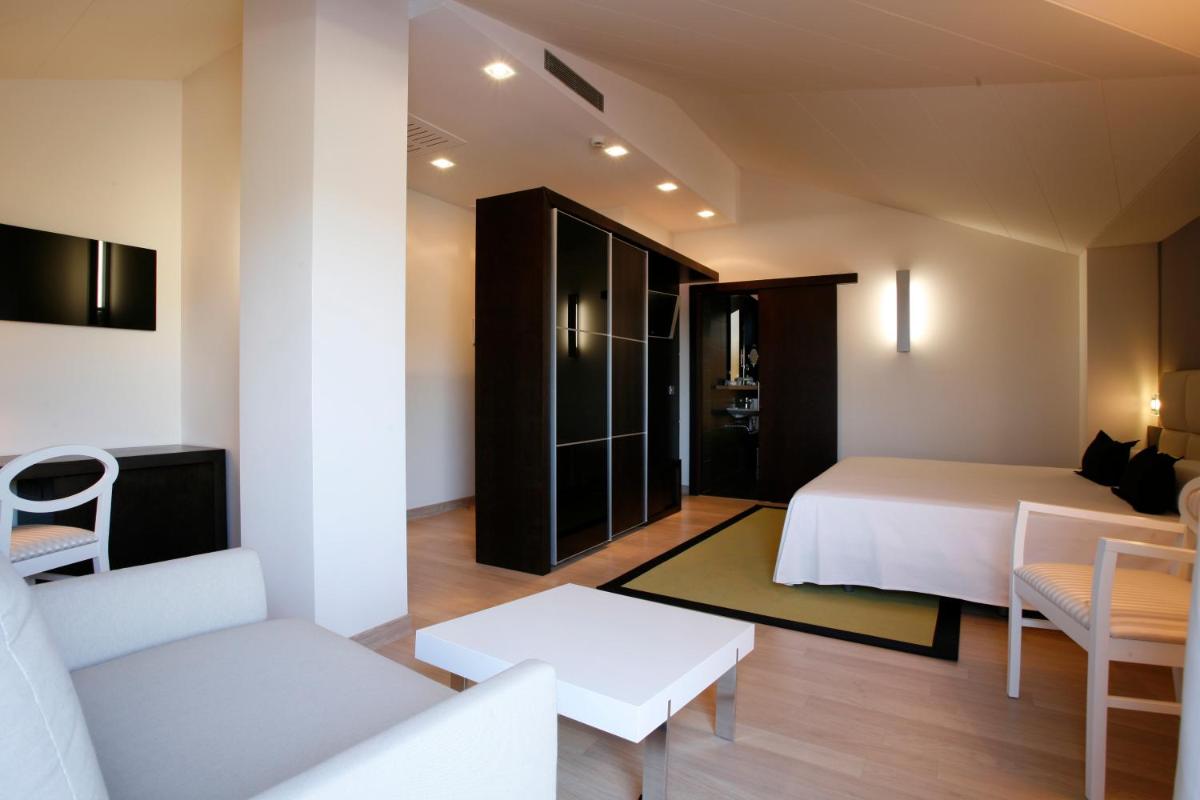 Un dormitorio con una cama y una sala de estar. en Hotel Bienestar Moaña, en Moaña