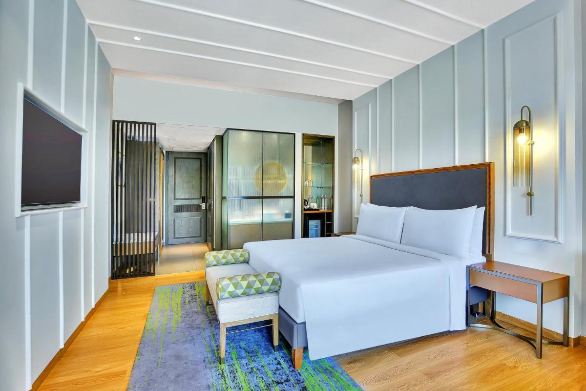 a bedroom with a white bed and a desk and a chair at Holiday Inn Goa Candolim in Candolim a bedroom with a white bed and a desk and a chair at Holiday Inn Goa Candolim in Candolim