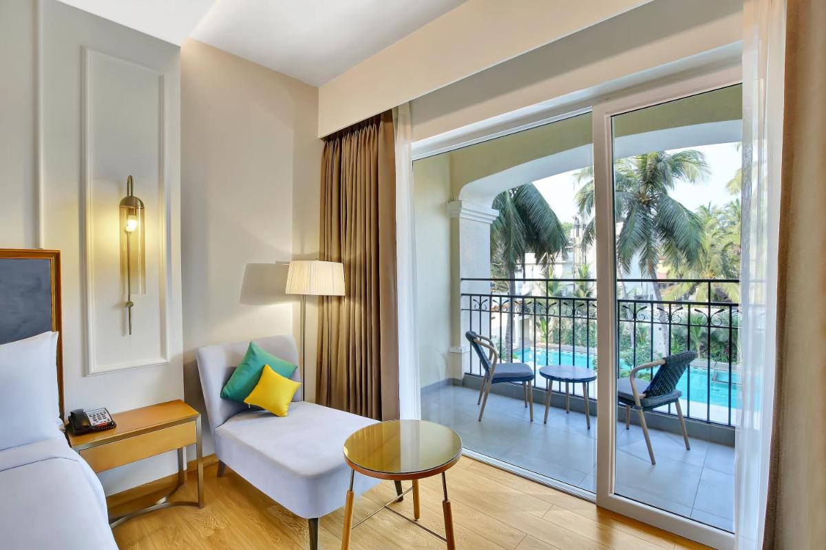 a room with a bed and a living room with a balcony at Holiday Inn Goa Candolim in Candolim a room with a bed and a living room with a balcony at Holiday Inn Goa Candolim in Candolim