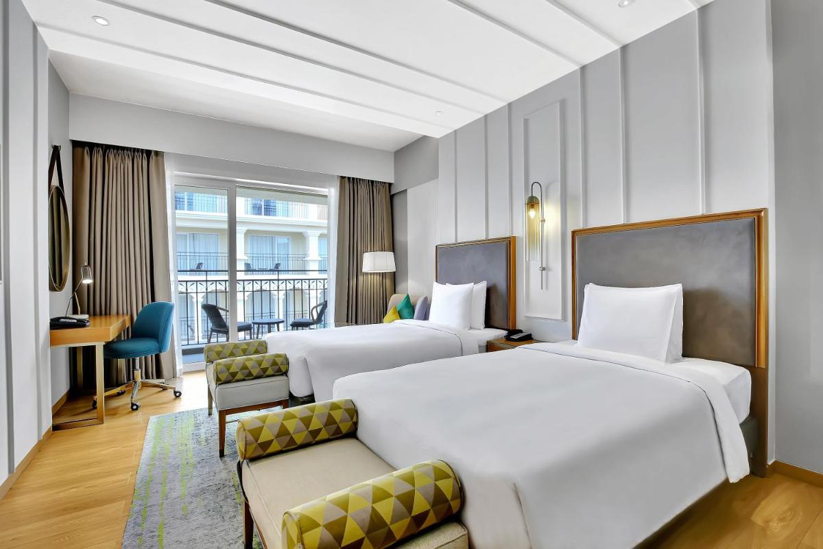 a hotel room with two beds and a desk at Holiday Inn Goa Candolim in Candolim a hotel room with two beds and a desk at Holiday Inn Goa Candolim in Candolim