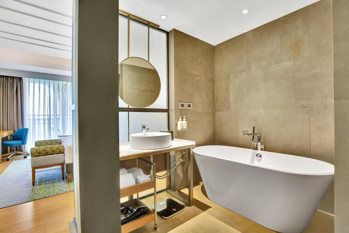 a bathroom with a white tub and a sink at Holiday Inn Goa Candolim in Candolim a bathroom with a white tub and a sink at Holiday Inn Goa Candolim in Candolim