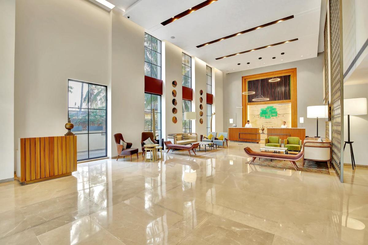 a lobby with couches and chairs in a building at Holiday Inn Goa Candolim in Candolim a lobby with couches and chairs in a building at Holiday Inn Goa Candolim in Candolim