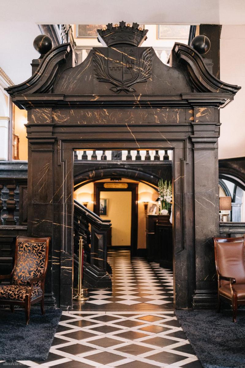 einen Eingang zu einem Gebäude mit einem karierten Boden in der Unterkunft Schlosshotel Hugenpoet in Essen