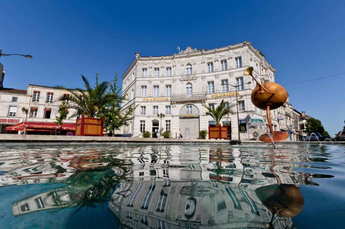 un bâtiment avec une réflexion dans l'eau en face de celui-ci dans l'établissement Hôtel François Premier Cognac Centre, à Cognac
