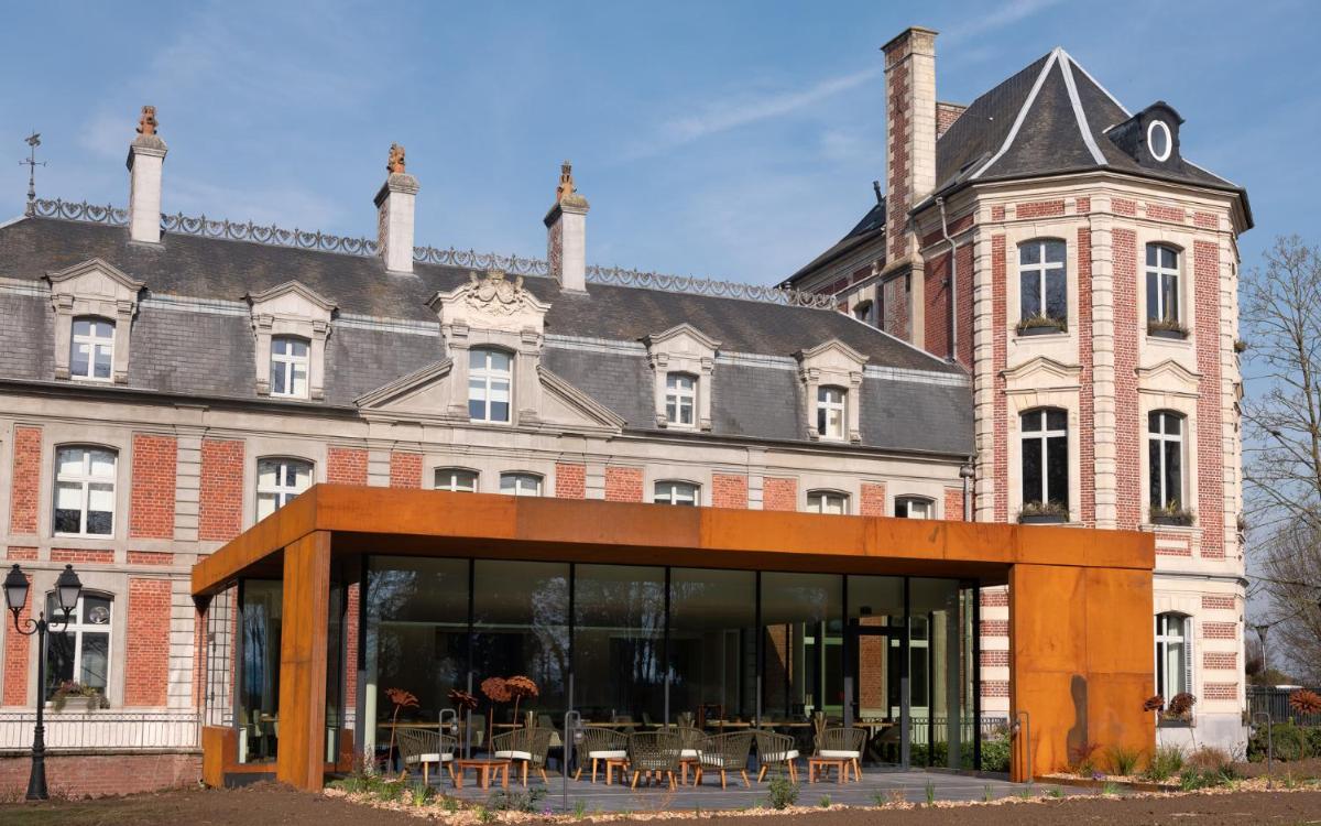 un grand bâtiment en briques avec des tables devant lui dans l'établissement Le Château De Beaulieu, à Busnes