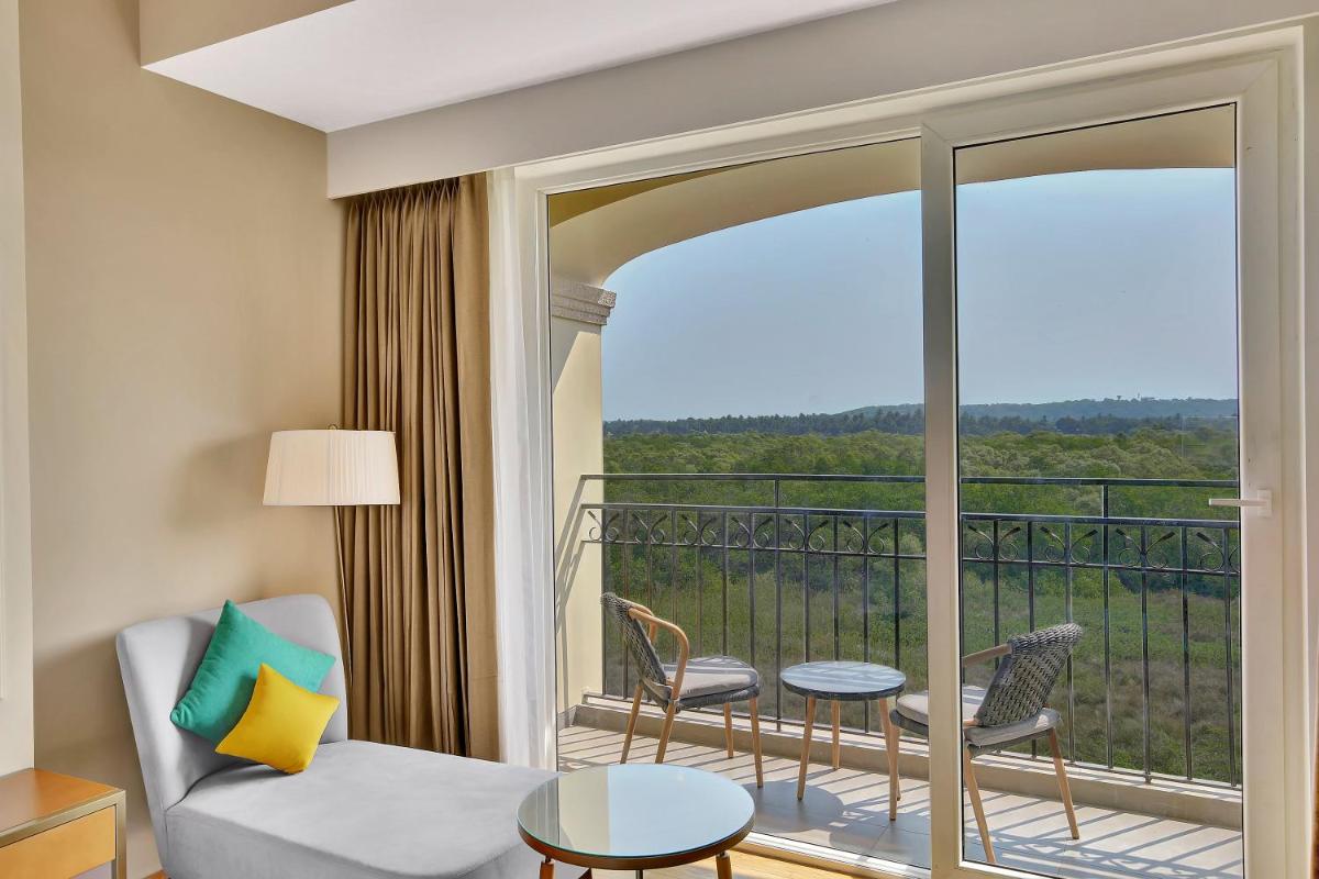 a room with a balcony with a couch and chairs at Holiday Inn Goa Candolim in Candolim a room with a balcony with a couch and chairs at Holiday Inn Goa Candolim in Candolim
