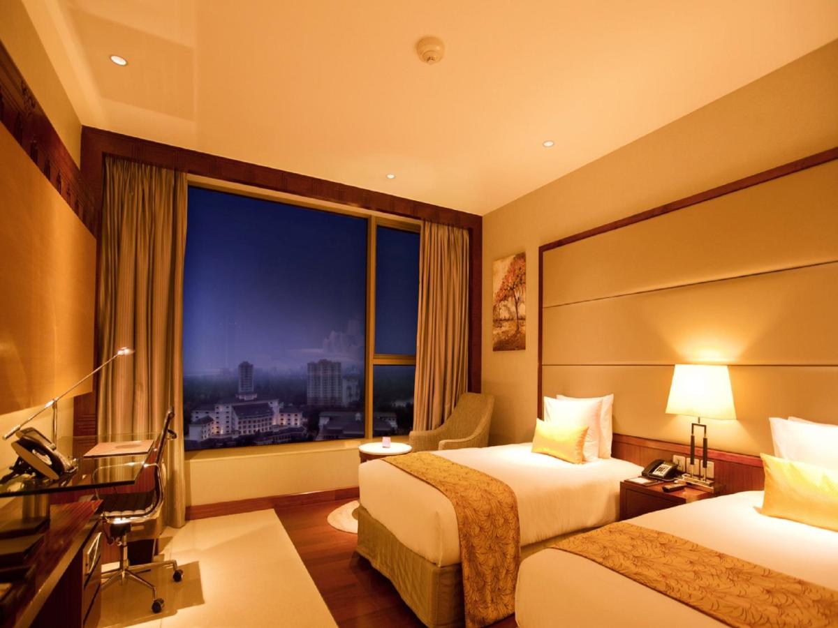 a hotel room with two beds and a window at Crowne Plaza Kochi by IHG in Cochin