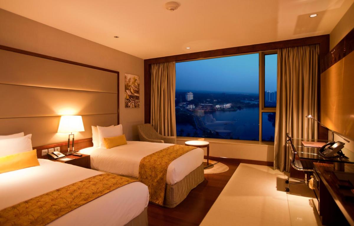 a hotel room with two beds and a large window at Crowne Plaza Kochi by IHG in Cochin