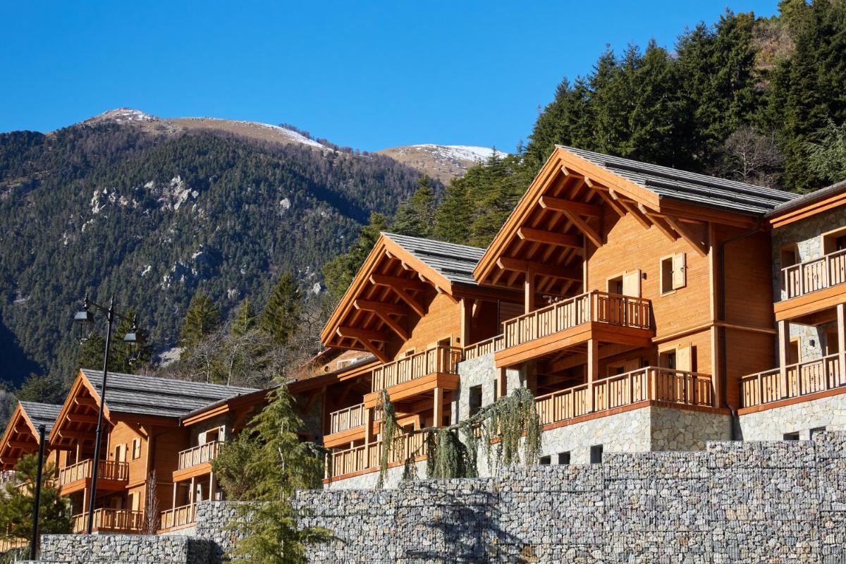 Une rangée d'immeubles d'appartements avec des montagnes en arrière-plan dans l'établissement Pure Montagne Resort & Spa, à Saint-Martin-Vésubie