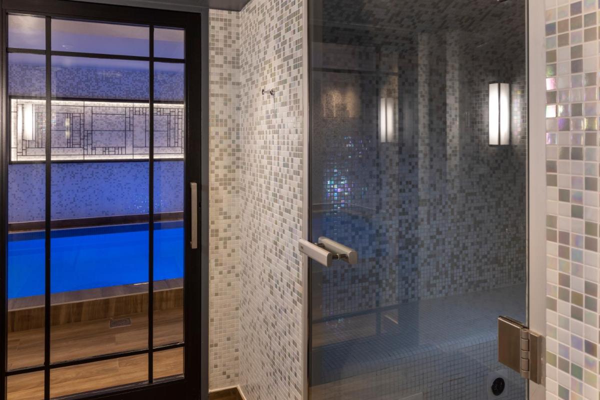 La salle de bains est pourvue d'une porte en verre menant à une piscine. dans l'établissement Les Matins de Paris & Spa, à Paris