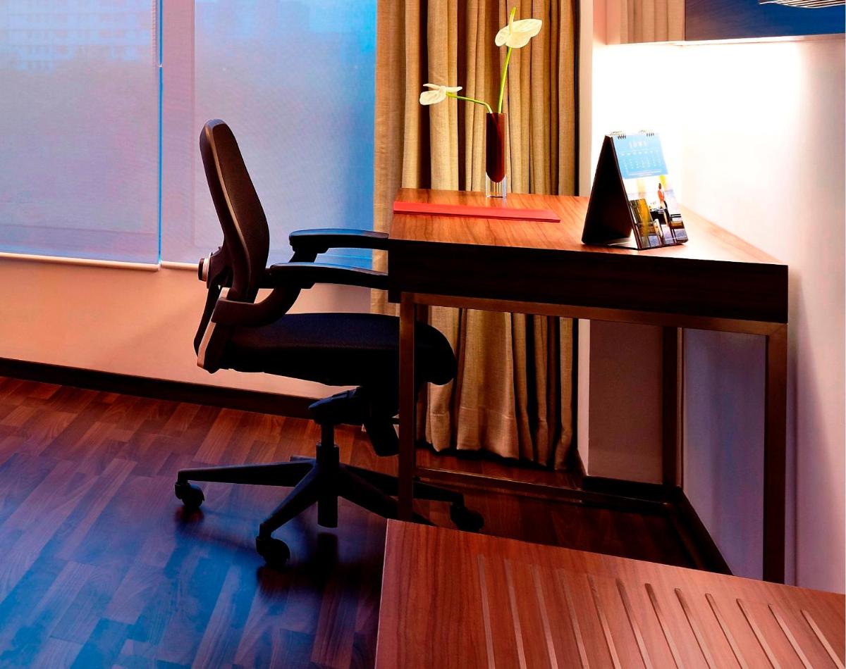 a desk with a chair next to a wooden desk at Vivanta Kolkata EM Bypass in Kolkata