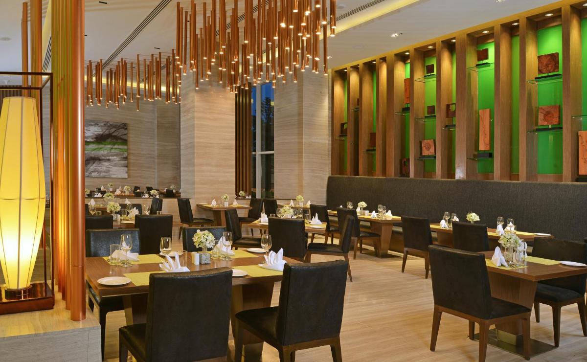 a restaurant with tables and chairs and a chandelier at Welcomhotel by ITC Hotels, Richmond Road, Bengaluru in Bengaluru