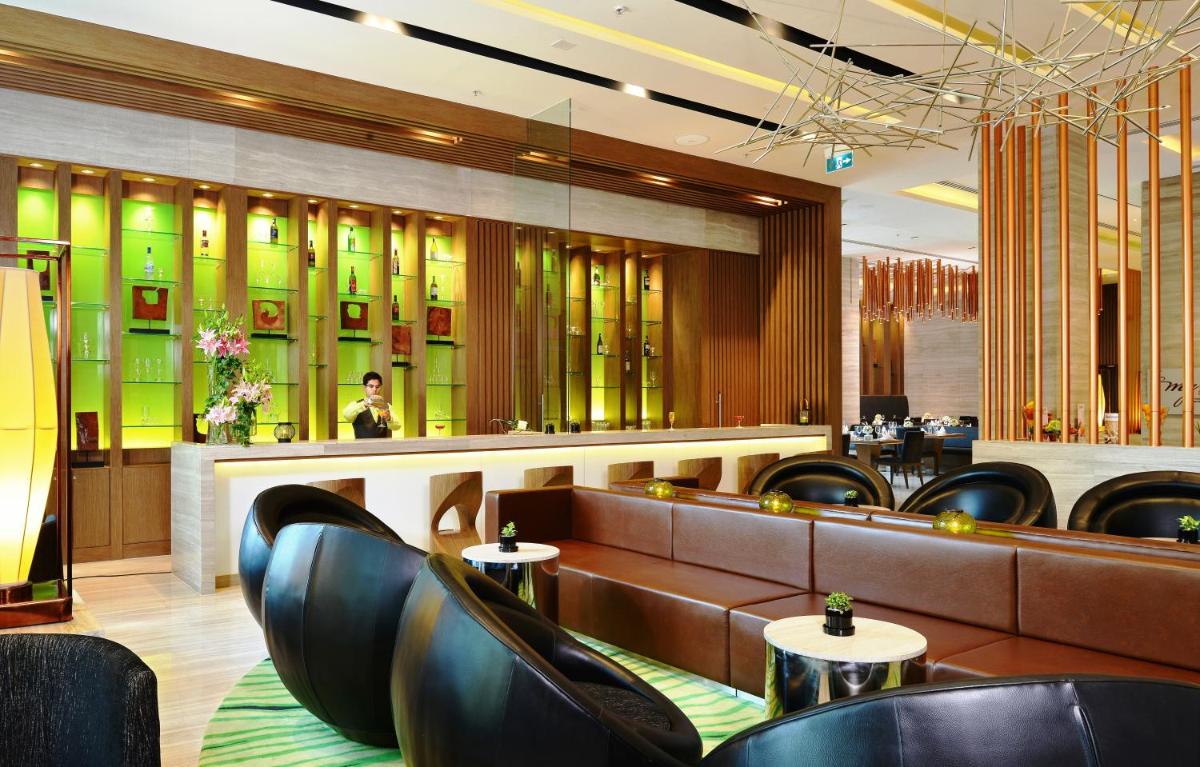 a restaurant with leather chairs and a bar at Welcomhotel by ITC Hotels, Richmond Road, Bengaluru in Bengaluru